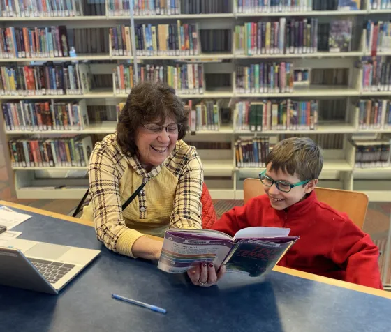 Brody and his tutor, Sue, read and giggle together at Brookdale Library.